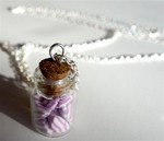 Sautoir avec fiole en verre remplie de berlingots en fimo roses et blancs